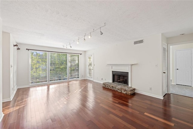 unfurnished living room with baseboards, wood finished floors, a fireplace, and a textured ceiling
