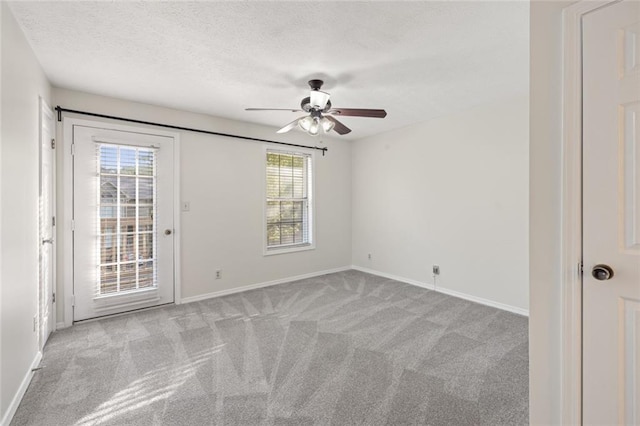 carpeted empty room with a ceiling fan, healthy amount of natural light, baseboards, and a textured ceiling