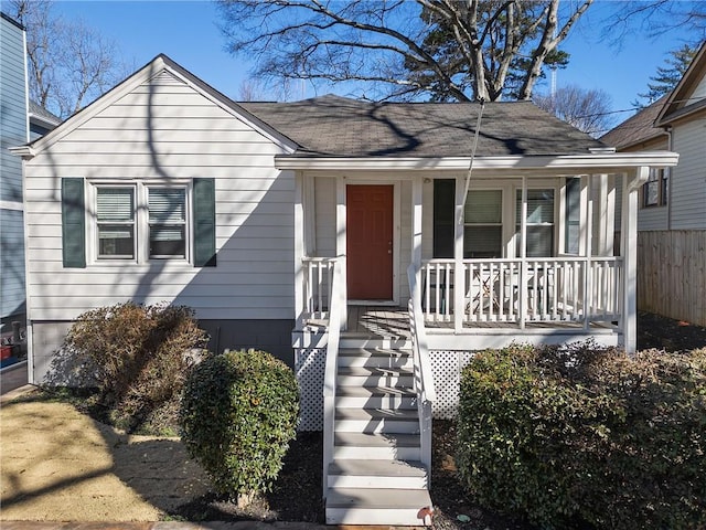 bungalow-style house with fence, a porch, and roof with shingles