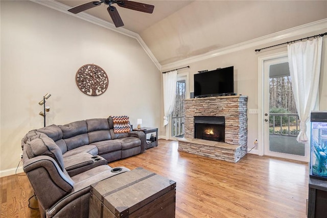 living area featuring a fireplace, ornamental molding, vaulted ceiling, wood finished floors, and baseboards