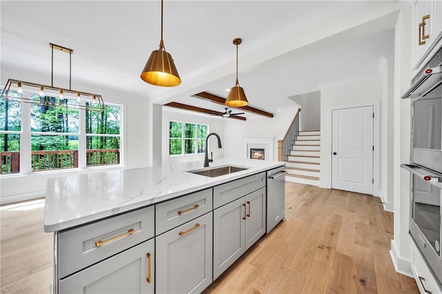 1664 Crestridge Dr SE, Marietta, GA 30067 - kitchen with gray cabinetry, dishwasher, a sink, light wood-type flooring, and a warm lit fireplace