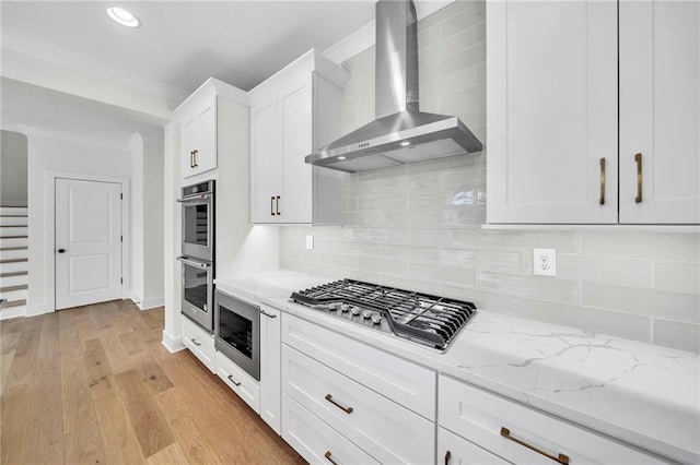 1664 Crestridge Dr SE, Marietta, GA 30067 - kitchen featuring wall chimney exhaust hood, appliances with stainless steel finishes, white cabinets, light stone counters, and light wood-style flooring