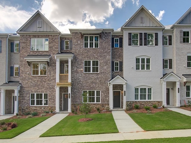 multi unit property featuring stone siding, brick siding, board and batten siding, and a front lawn