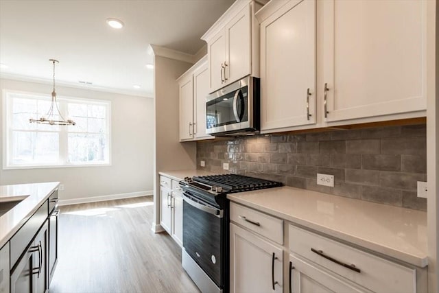 kitchen featuring decorative light fixtures, backsplash, stainless steel appliances, crown molding, and light countertops