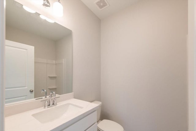 full bathroom featuring visible vents, toilet, vanity, and walk in shower