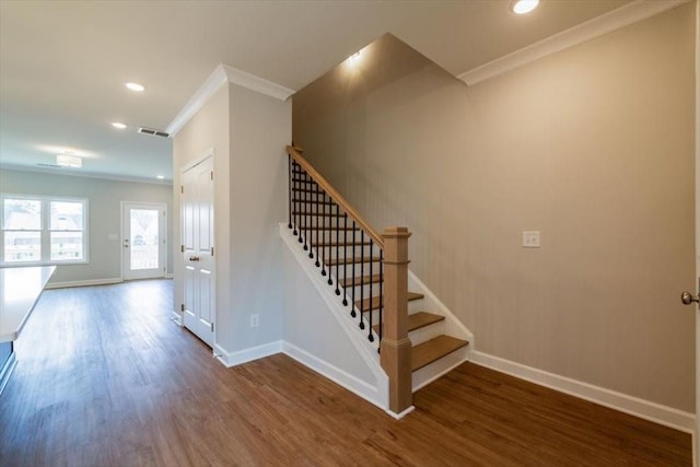 stairs featuring visible vents, baseboards, wood finished floors, and ornamental molding