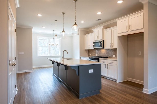 kitchen featuring a kitchen island with sink, stainless steel appliances, white cabinets, crown molding, and backsplash