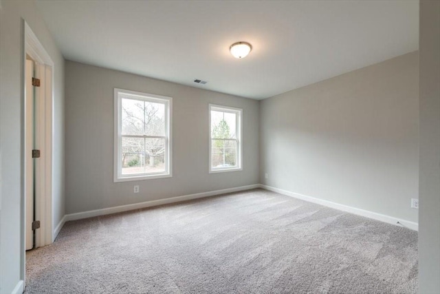 empty room featuring carpet, visible vents, and baseboards