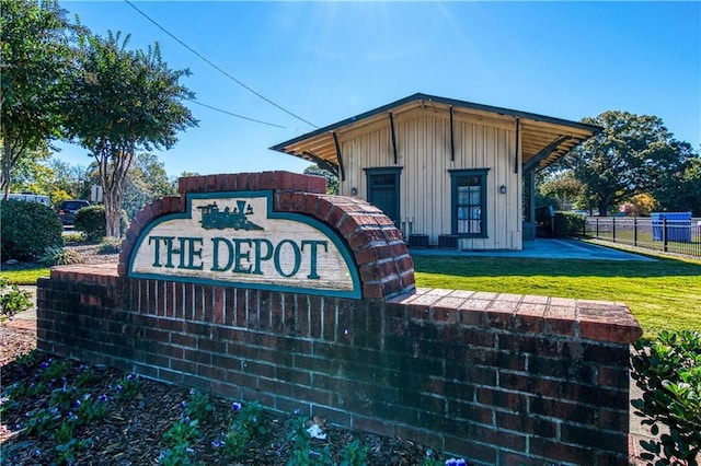 community / neighborhood sign with a lawn and fence