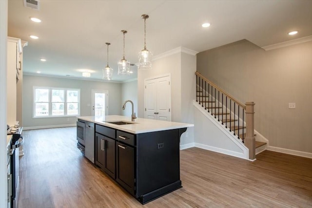 kitchen with visible vents, light wood-style flooring, ornamental molding, a sink, and light countertops