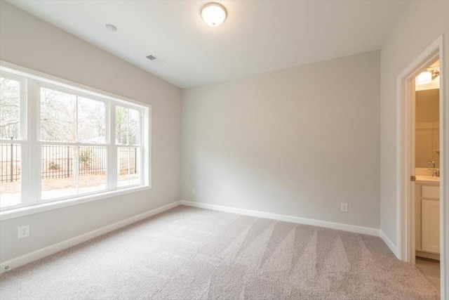 unfurnished room with visible vents, baseboards, and light colored carpet