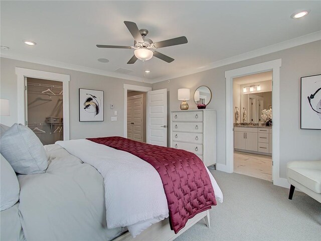 carpeted bedroom featuring a walk in closet, a closet, ceiling fan, and ornamental molding