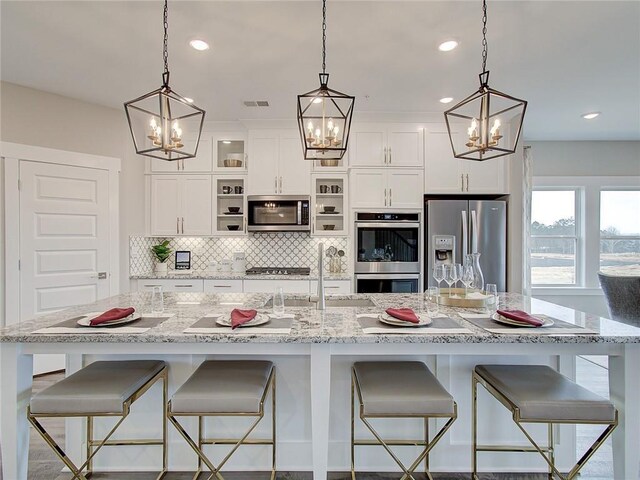 kitchen featuring appliances with stainless steel finishes, white cabinetry, a breakfast bar area, and backsplash