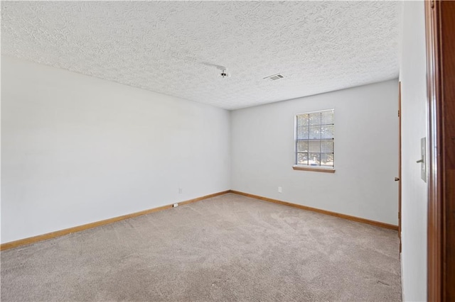 carpeted empty room featuring a textured ceiling