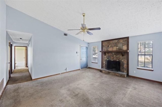 unfurnished living room featuring lofted ceiling, a stone fireplace, carpet flooring, ceiling fan, and a textured ceiling