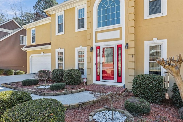 entrance to property featuring stucco siding, a garage, and concrete driveway