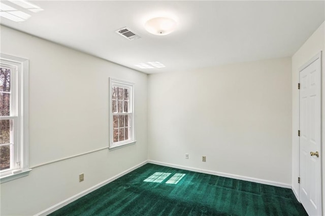 unfurnished room with baseboards, plenty of natural light, visible vents, and dark carpet