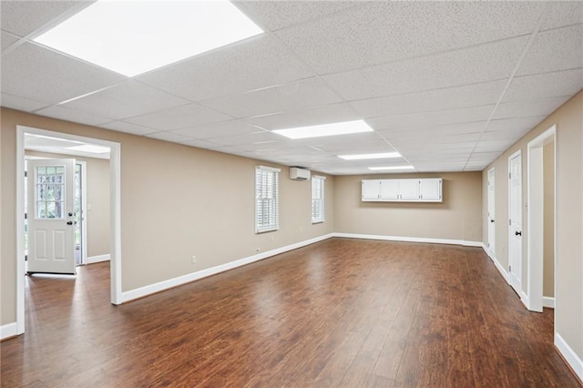 basement featuring dark wood finished floors, a paneled ceiling, and baseboards