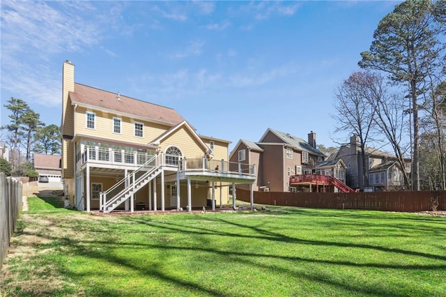 rear view of property featuring a deck, stairs, fence, a yard, and a chimney