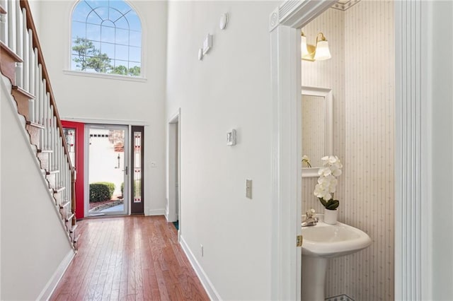 entryway featuring stairway, a towering ceiling, a healthy amount of sunlight, and wood-type flooring