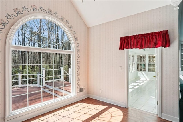 entryway featuring baseboards, wallpapered walls, lofted ceiling, and wood finished floors