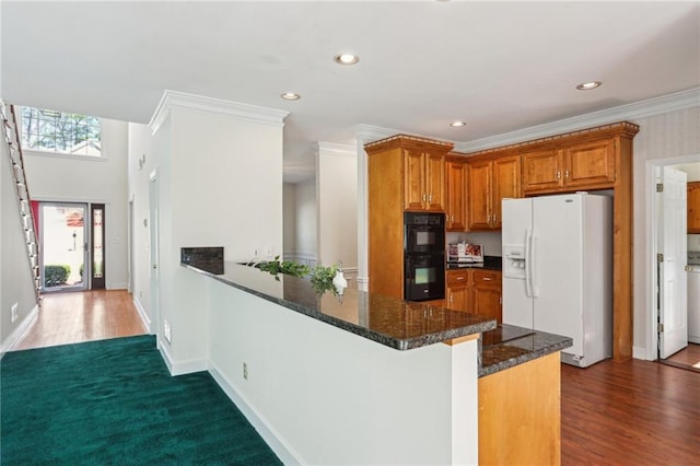 kitchen featuring brown cabinetry, a peninsula, ornamental molding, white fridge with ice dispenser, and dobule oven black