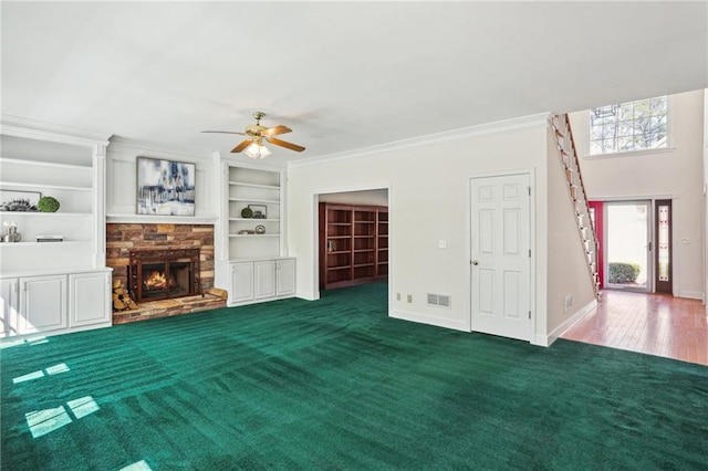 unfurnished living room featuring carpet, baseboards, visible vents, a fireplace, and ornamental molding