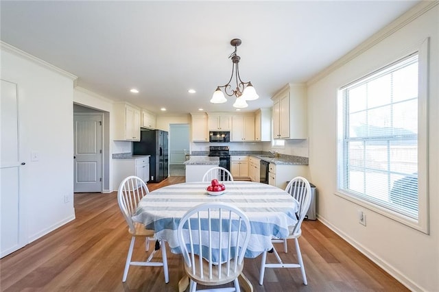 dining room featuring an inviting chandelier, light wood-type flooring, crown molding, and plenty of natural light