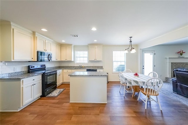 kitchen with hardwood / wood-style floors, a chandelier, black appliances, hanging light fixtures, and light stone countertops