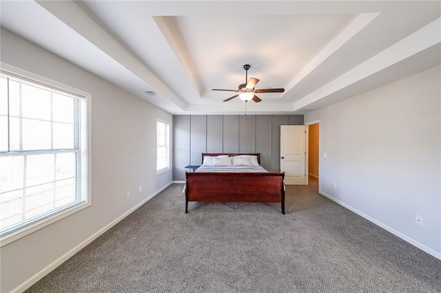 unfurnished bedroom with a raised ceiling, ceiling fan, and carpet