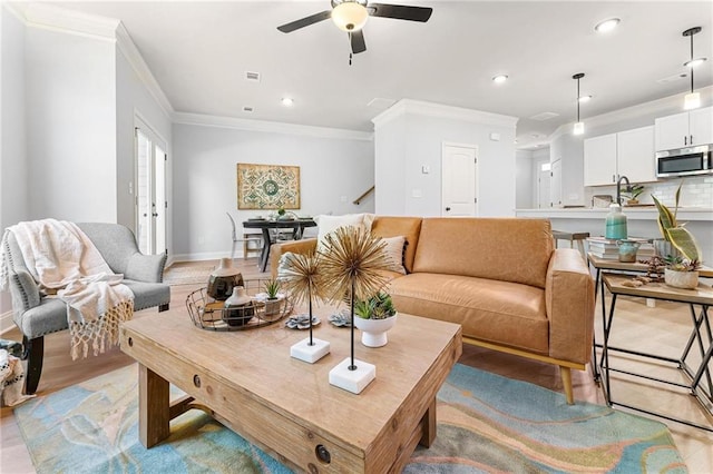 living room with light hardwood / wood-style floors, crown molding, and ceiling fan