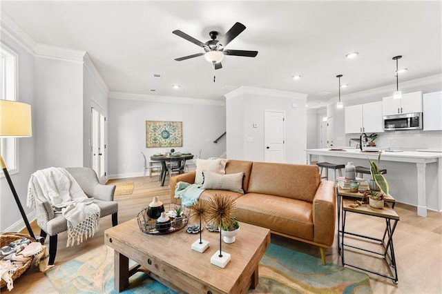 living room with crown molding, light hardwood / wood-style floors, and ceiling fan