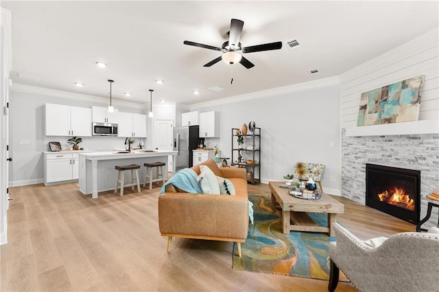 living room with crown molding, light hardwood / wood-style flooring, and a fireplace