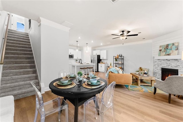 dining area with ornamental molding, light hardwood / wood-style flooring, and a fireplace