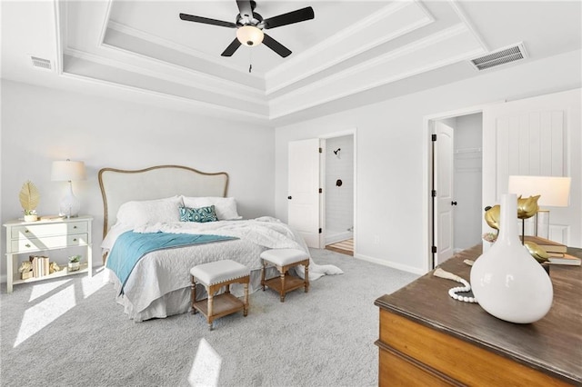 carpeted bedroom with a walk in closet, a tray ceiling, a closet, and ceiling fan