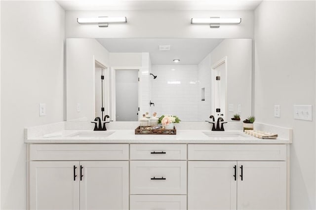 bathroom with a tile shower and vanity