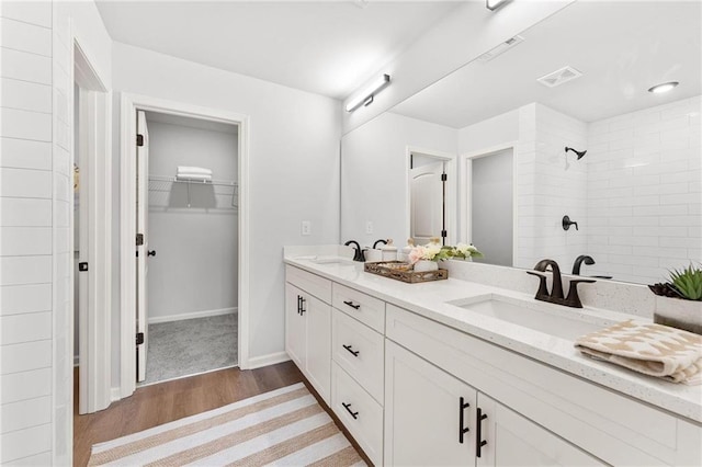 bathroom with vanity, a tile shower, and wood-type flooring