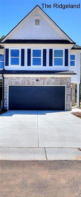 view of front of house with a garage, stone siding, and concrete driveway