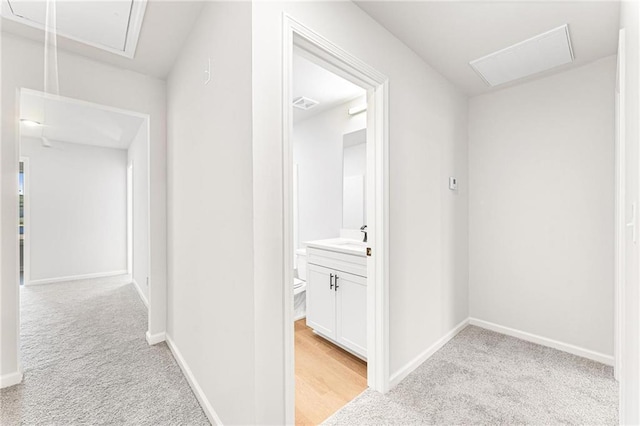 hallway featuring light carpet and sink