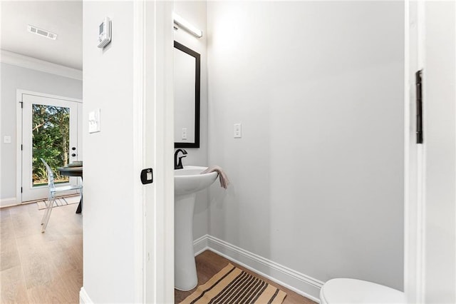 bathroom with toilet, ornamental molding, and hardwood / wood-style floors