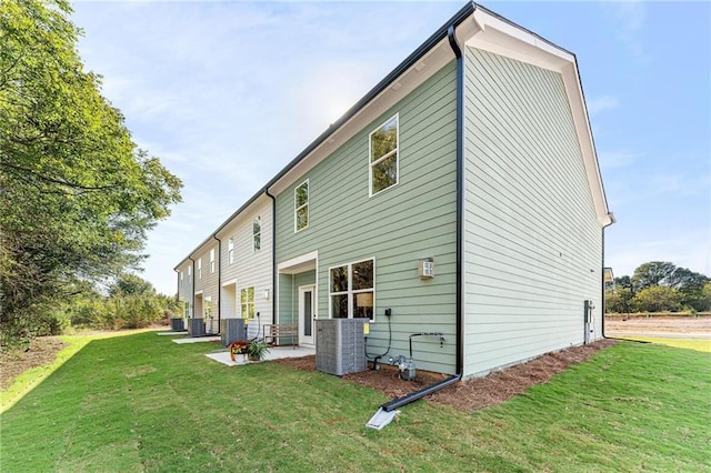 rear view of house with central air condition unit, a patio area, and a yard