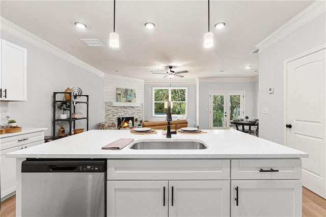 kitchen with hanging light fixtures, sink, stainless steel dishwasher, and white cabinets