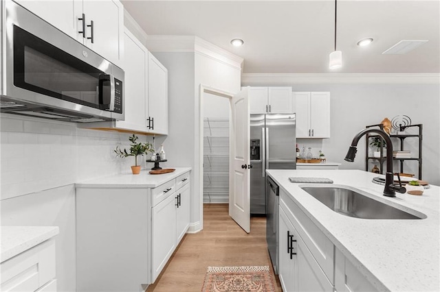 kitchen featuring hanging light fixtures, stainless steel appliances, sink, white cabinetry, and light hardwood / wood-style floors