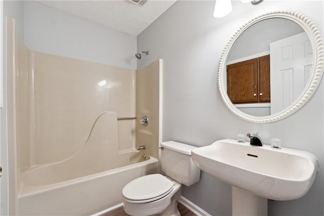 full bathroom featuring a textured ceiling, shower / bath combination, toilet, and sink