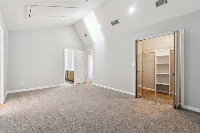 unfurnished bedroom with high vaulted ceiling, a walk in closet, ensuite bath, carpet flooring, and a closet