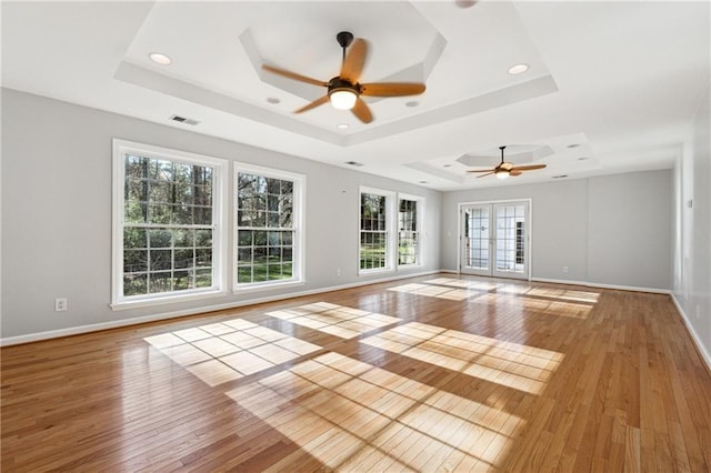 unfurnished room with ceiling fan, light hardwood / wood-style floors, and a raised ceiling