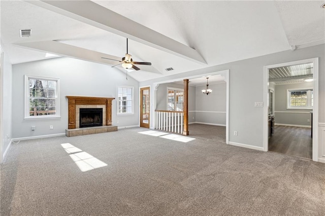 unfurnished living room featuring carpet flooring, a tiled fireplace, lofted ceiling with beams, and ceiling fan with notable chandelier