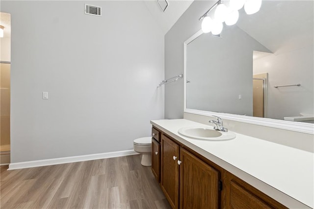 bathroom with vaulted ceiling, hardwood / wood-style flooring, toilet, and a shower with door