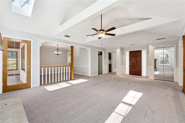 unfurnished living room with ceiling fan with notable chandelier, light colored carpet, and lofted ceiling with skylight