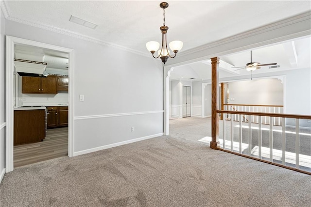 carpeted spare room featuring decorative columns, ceiling fan with notable chandelier, and ornamental molding